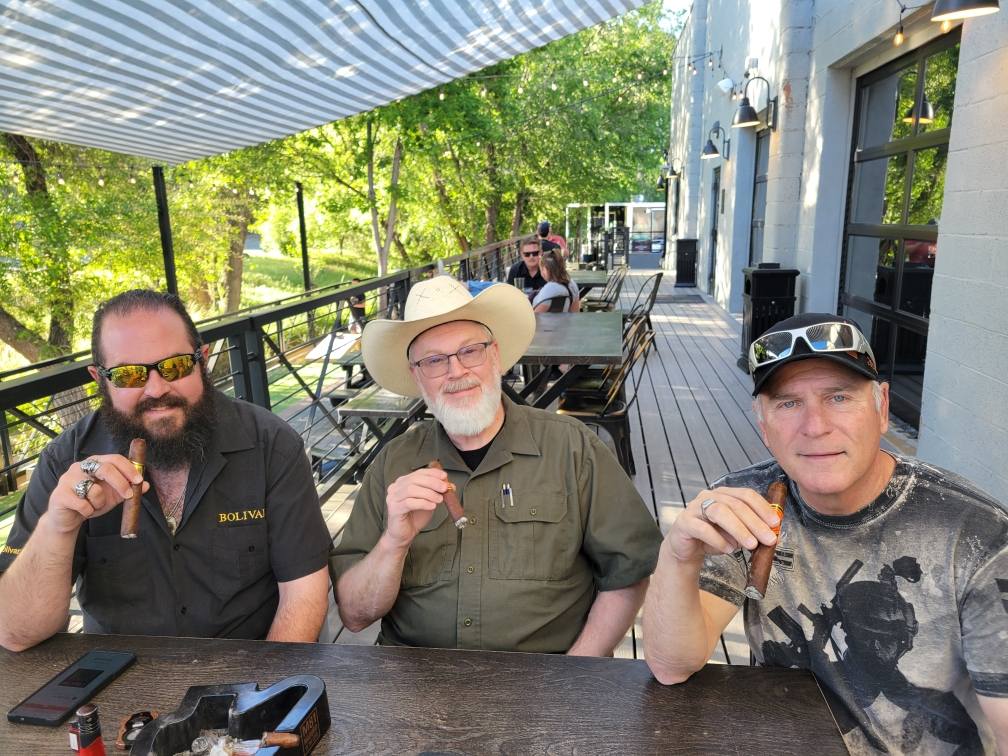 locals holding beers playing cornhole at Founding Fathers Collective Patio Area